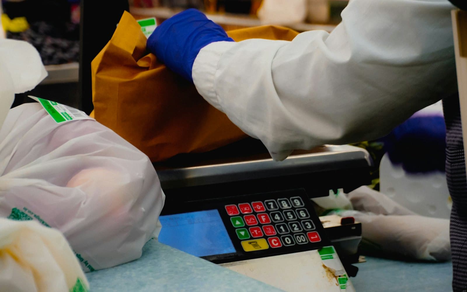 A supermarket checkout with groceries being bagged beside the register scale.