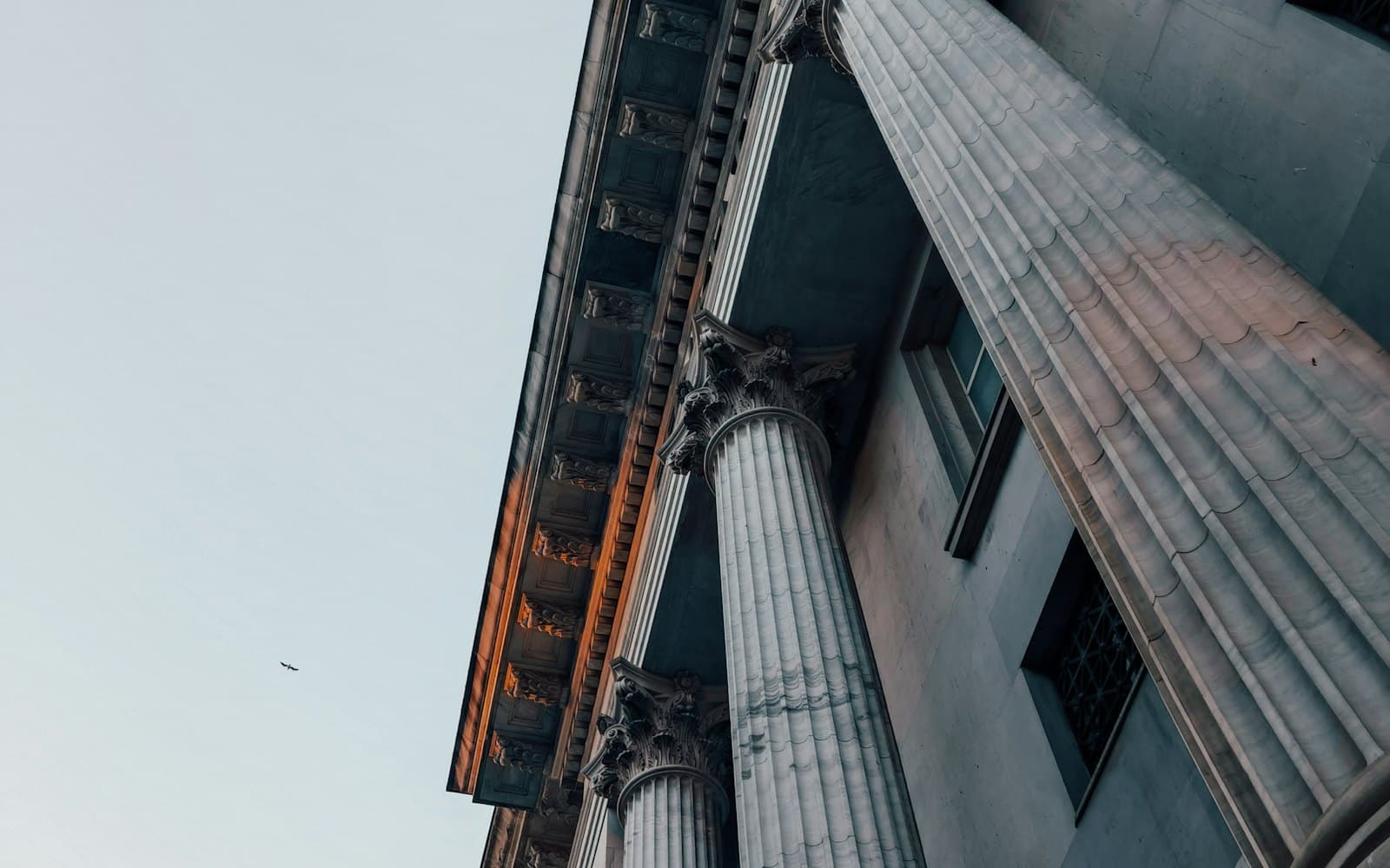 Looking up at the stone columns and facade of a classical bank building.