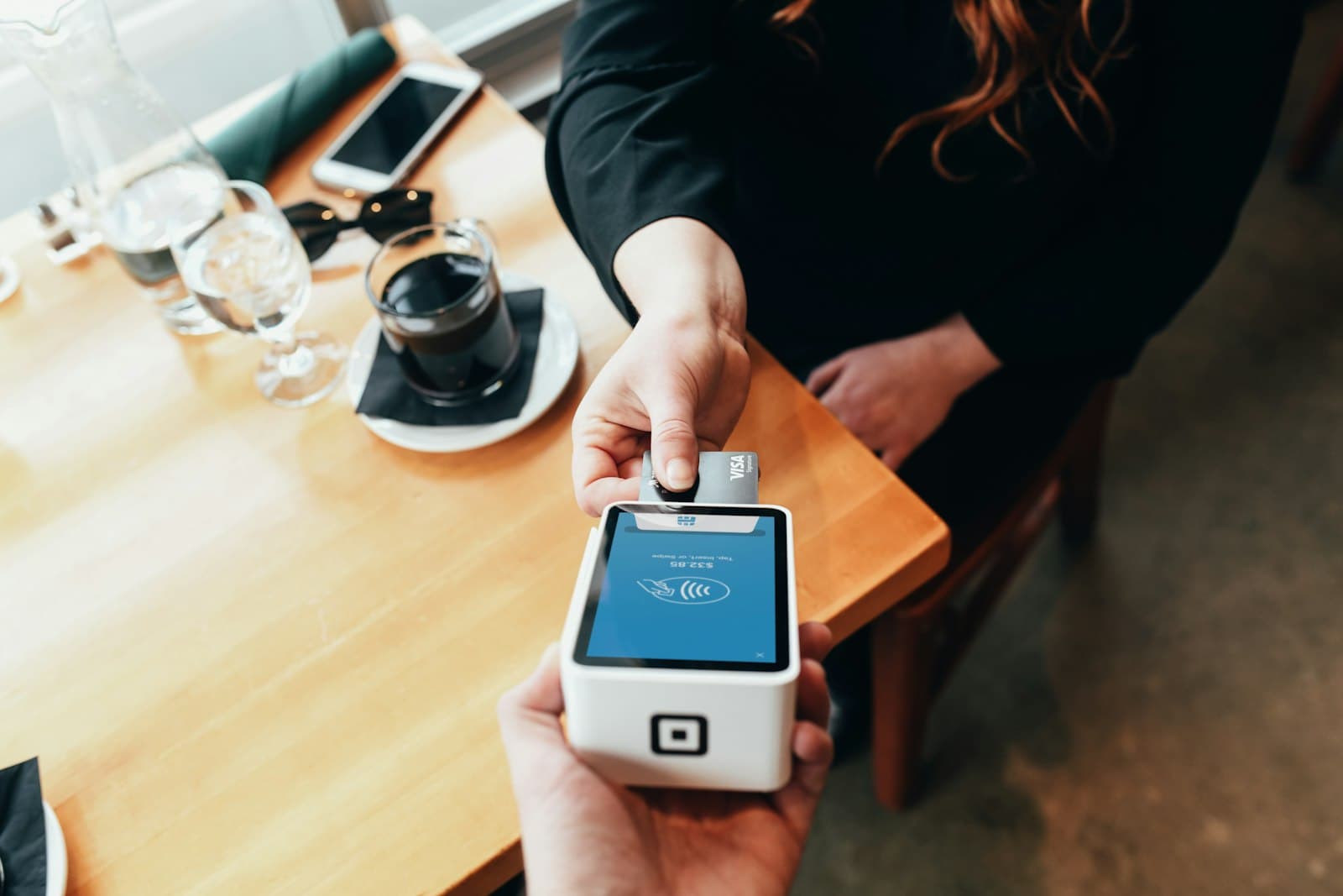 A person paying by card on a payment terminal at a counter.