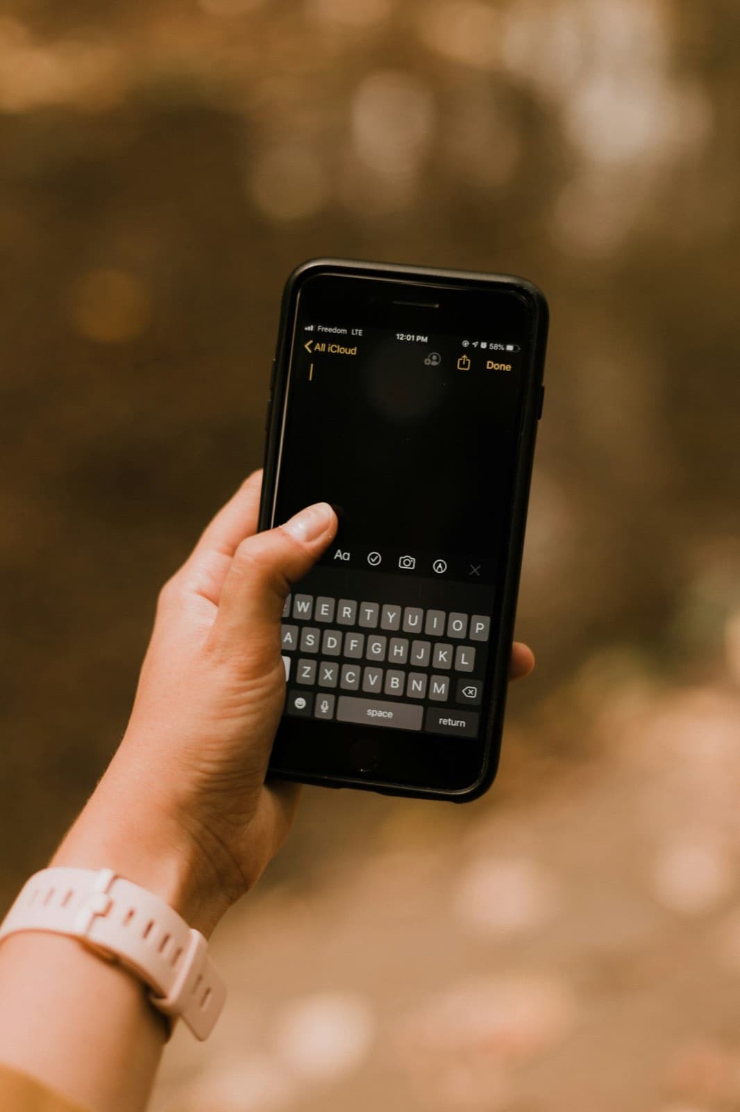 A hand holding a smartphone with a note-taking app open.