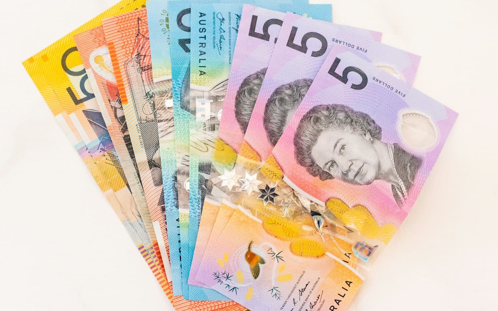 Assorted Australian banknotes fanned out on a pale surface.