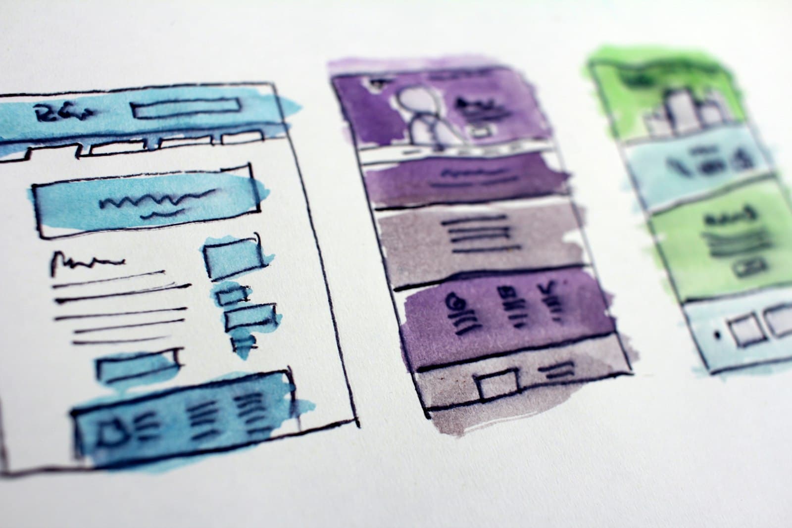 Watercolour wireframe sketches of mobile app screens laid out on paper.