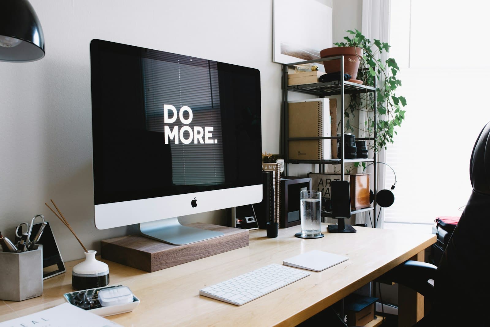 A tidy desk with a large monitor displaying the words Do More.