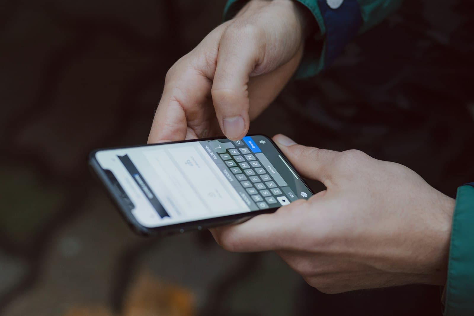 A person's hands typing on a smartphone held close to the camera.