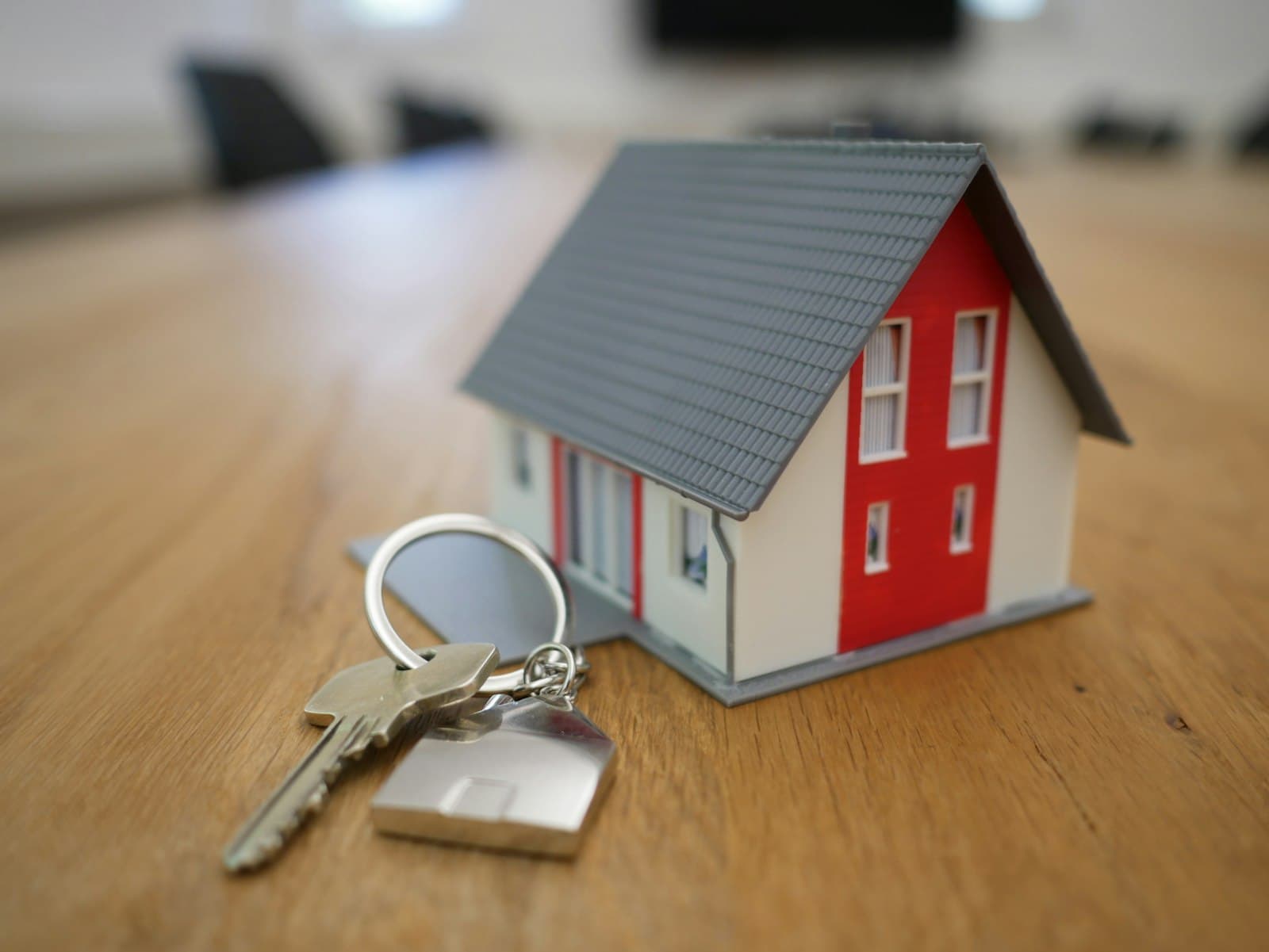 A model house and a set of keys on a table, standing in for the assets and debts that make up home equity.