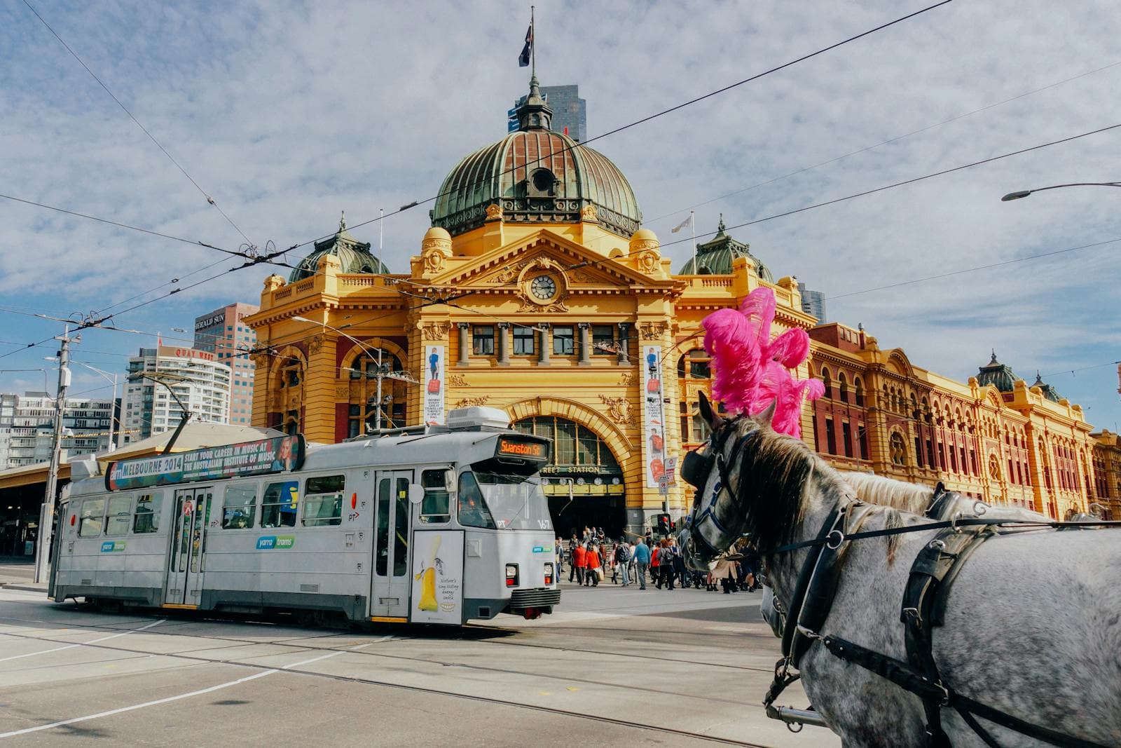 Flinders Street Station in Melbourne with a tram passing, everyday city life for people in their twenties.