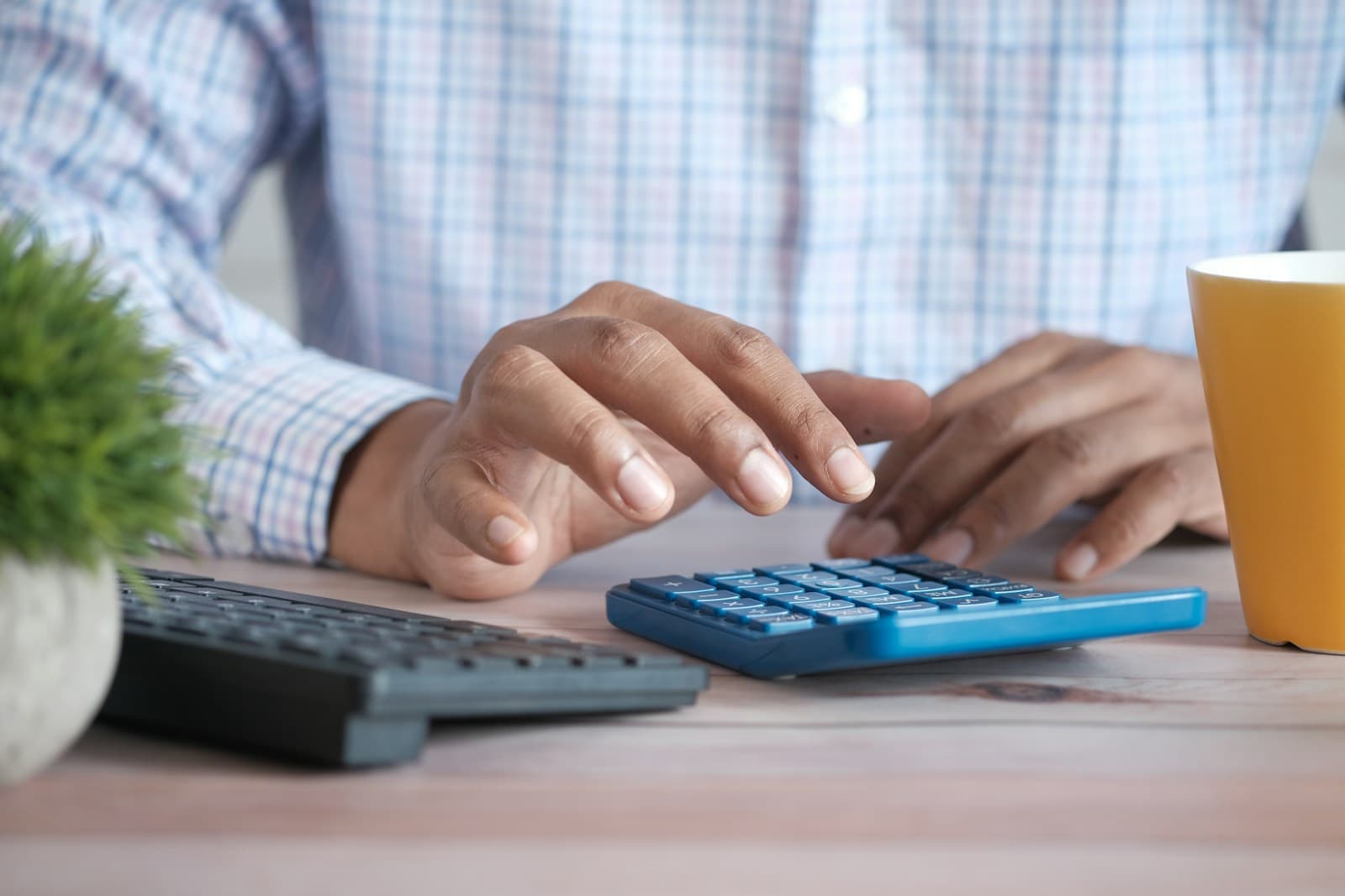 A person working through loan interest figures on a desktop calculator at a desk.