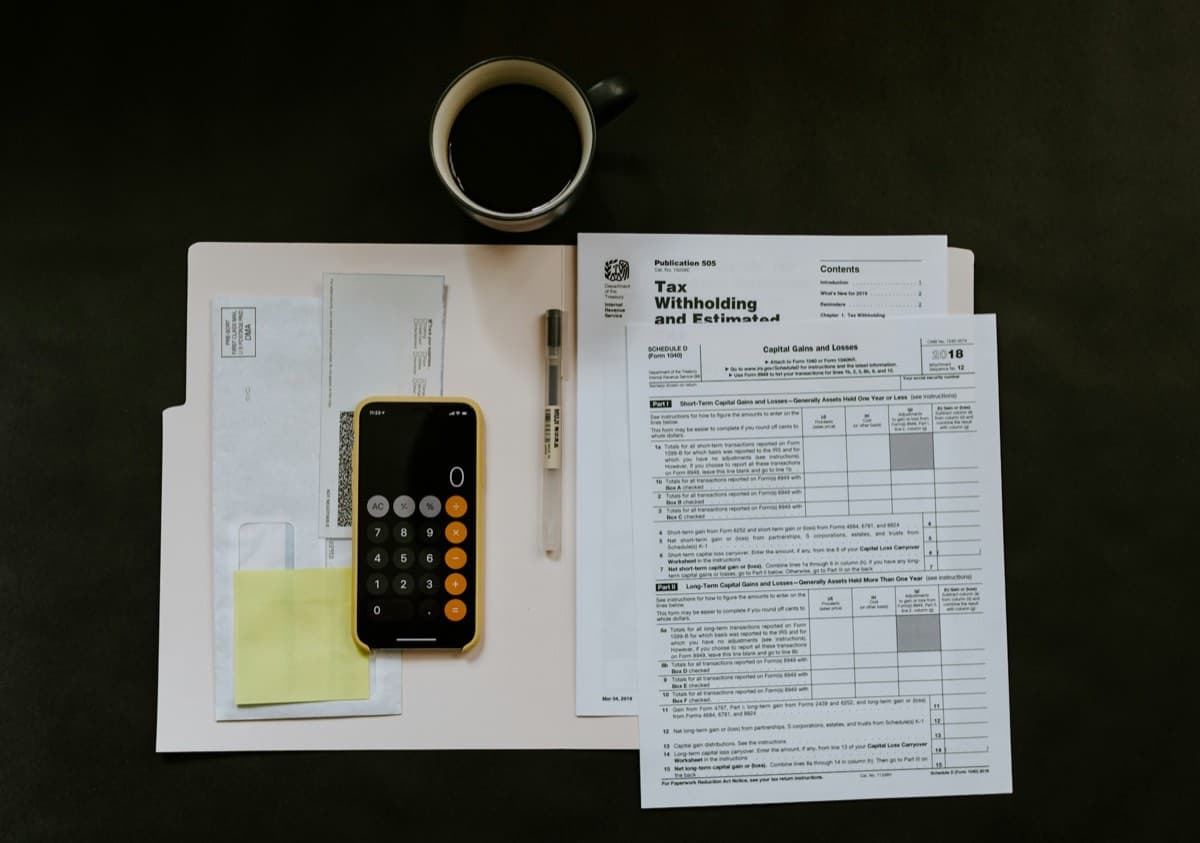 Mortgage and tax paperwork beside a pen and phone on a desk.