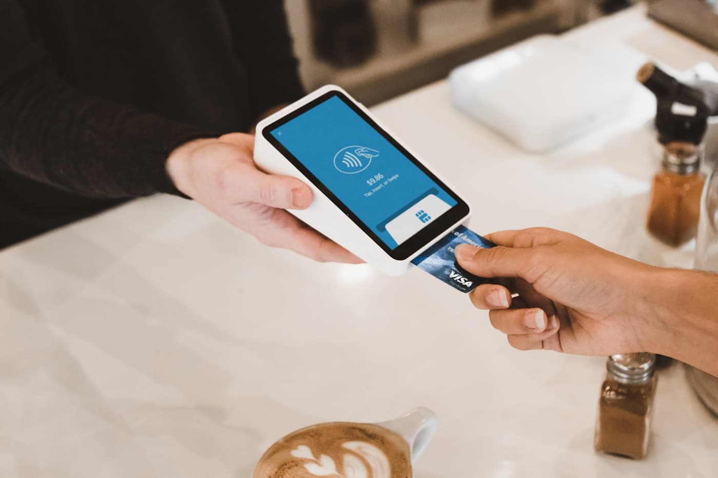 A customer inserting a bank card into a payment terminal at a cafe counter.