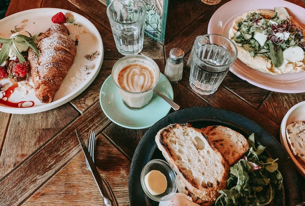 A cafe table with brunch plates, coffee and water glasses viewed from above.