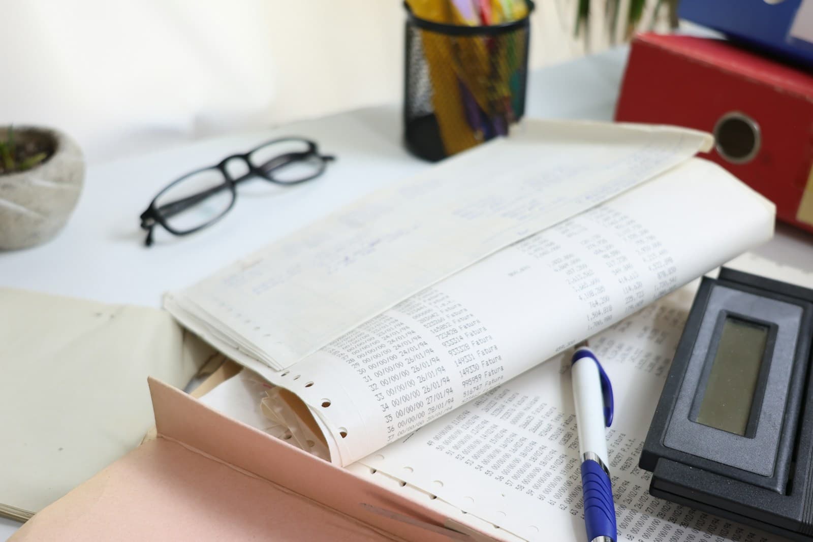 A desk covered in printed statements and folders with a calculator, the manual side of property tracking.